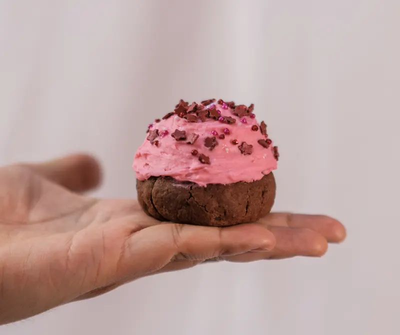 Galleta con betún rosa en la palma de la mano